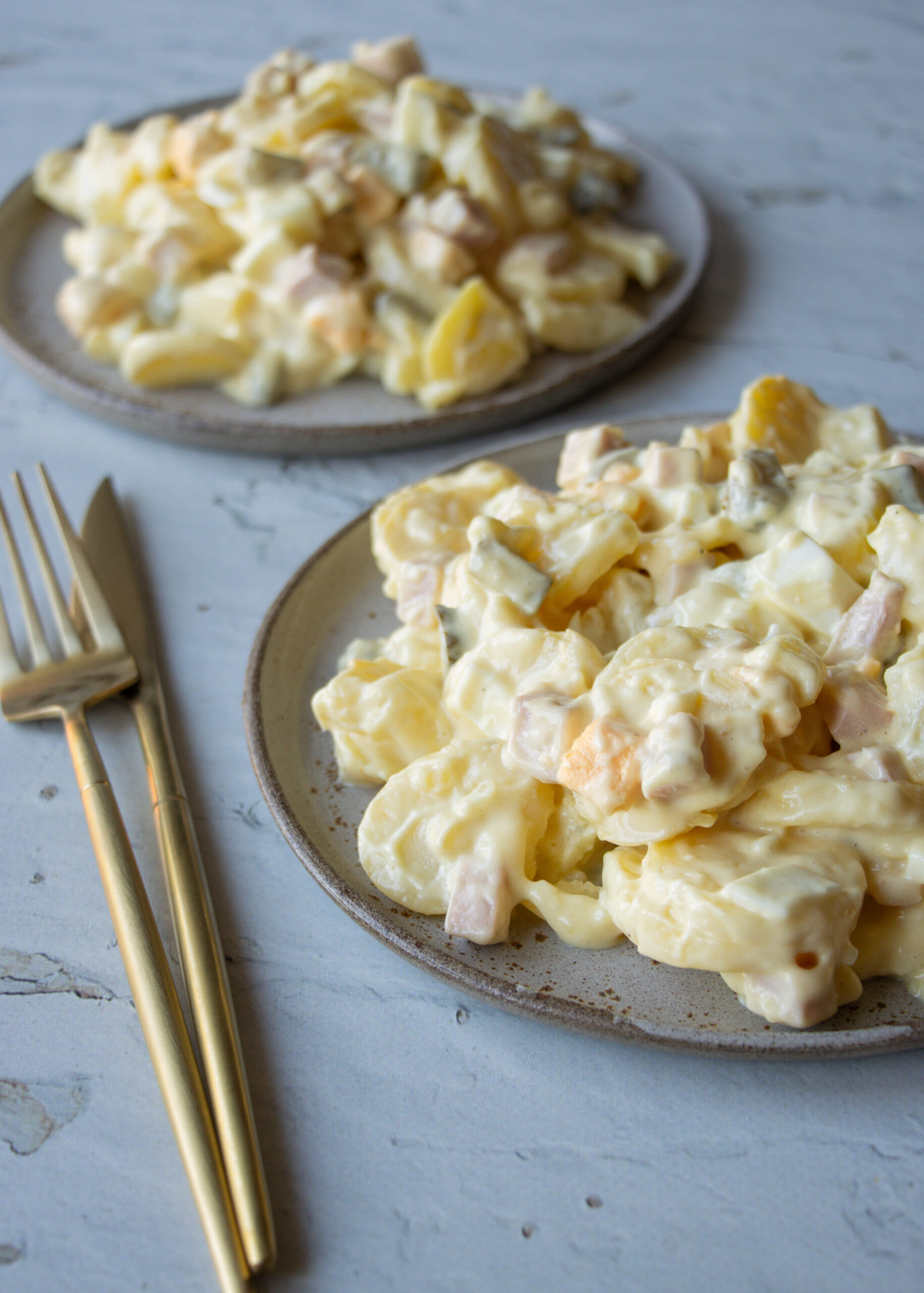 deftiger Kartoffelsalat auf zwei Tellern angerichtet